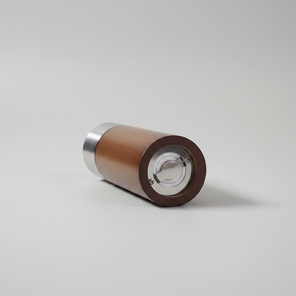 Wooden cylindrical object with metallic accents on a white surface
