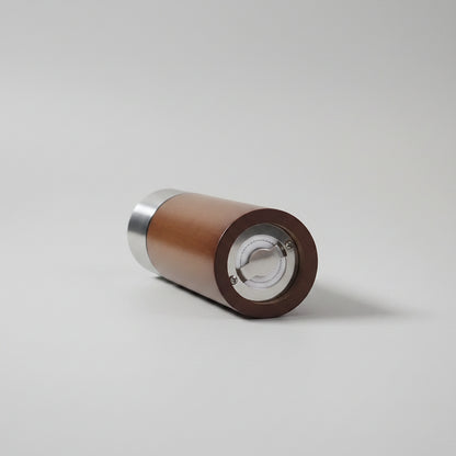 Wooden cylindrical object with metallic accents on a white surface